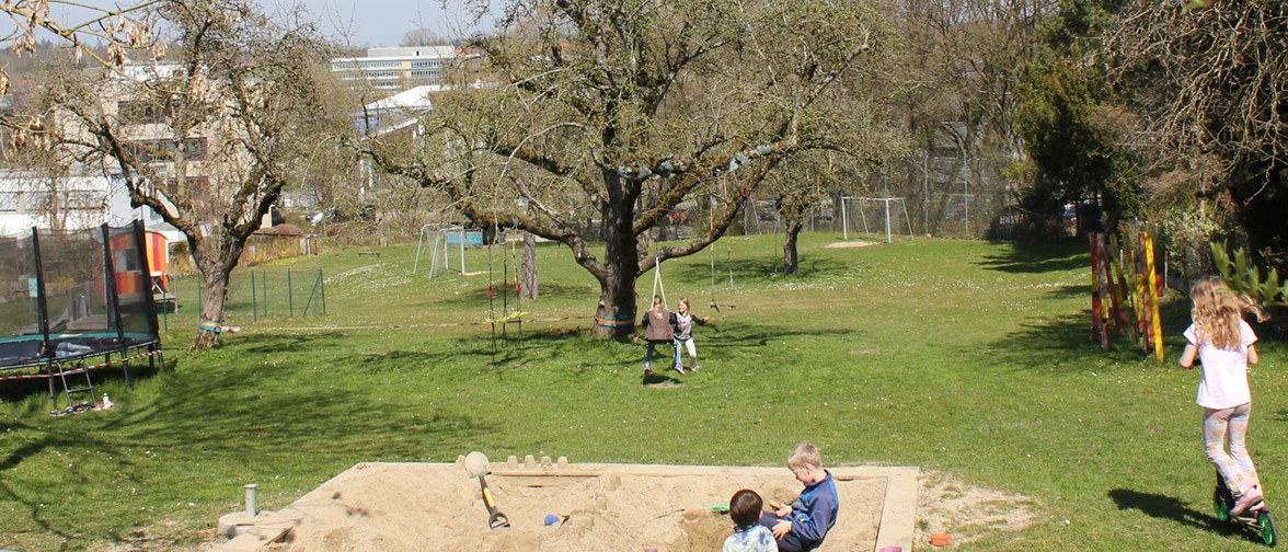Large garden with mature trees and lawn at the TUM after-school care center in Weihenstephan.