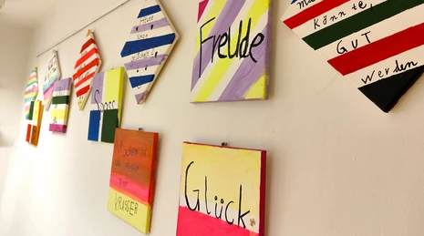 Wall boards in the TUM daycare center with the words “happiness,” “joy,” “fun,” and positive sayings.